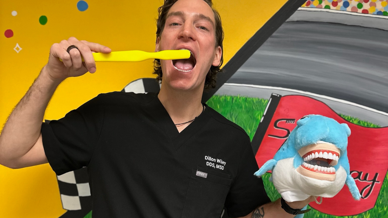 Dr Wiley holding a toothbrush and shark stufftoy